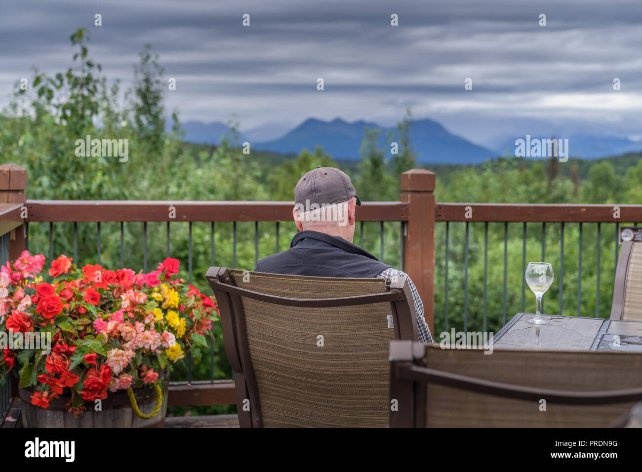 A senior man set on the deck of resort hotel lodge with glass of wine Stock Photo