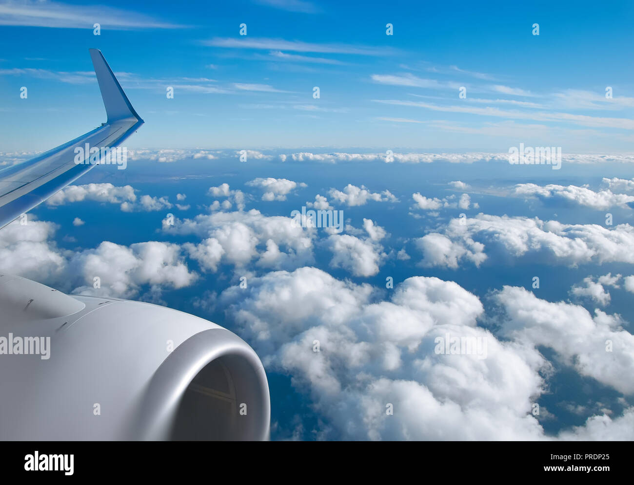Aerial view of clouds, horizon, blue sky and plane wing view through the airplane window. Stock Photo
