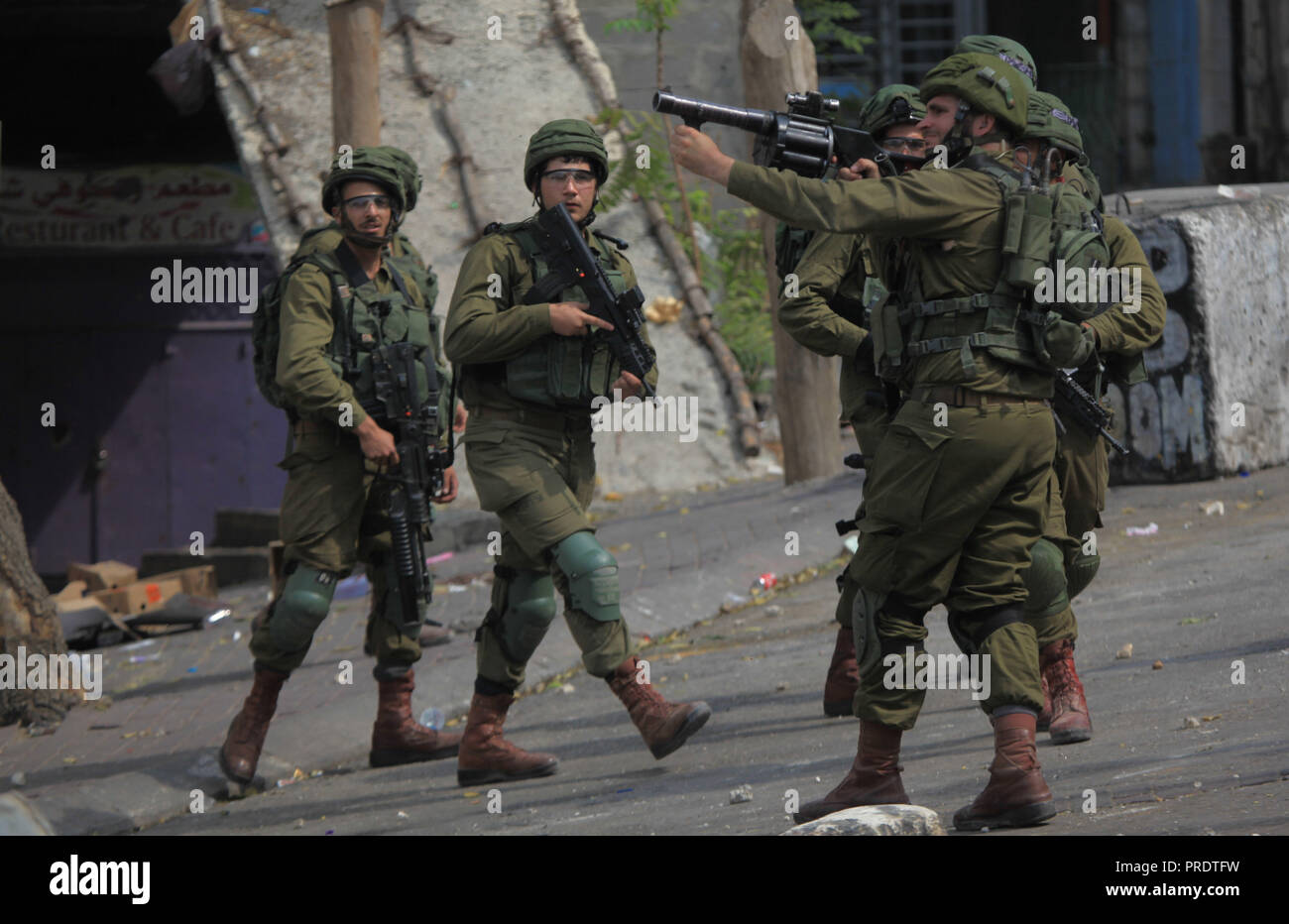 Hebron, West Bank City of Hebron. 1st Oct, 2018. An Israeli soldier fires a tear gas canister at Palestinian protesters during clashes after a protest against the recently passed Jewish nation state law, in the West Bank City of Hebron, on Oct. 1, 2018. Credit: Mamoun Wazwaz/Xinhua/Alamy Live News Stock Photo