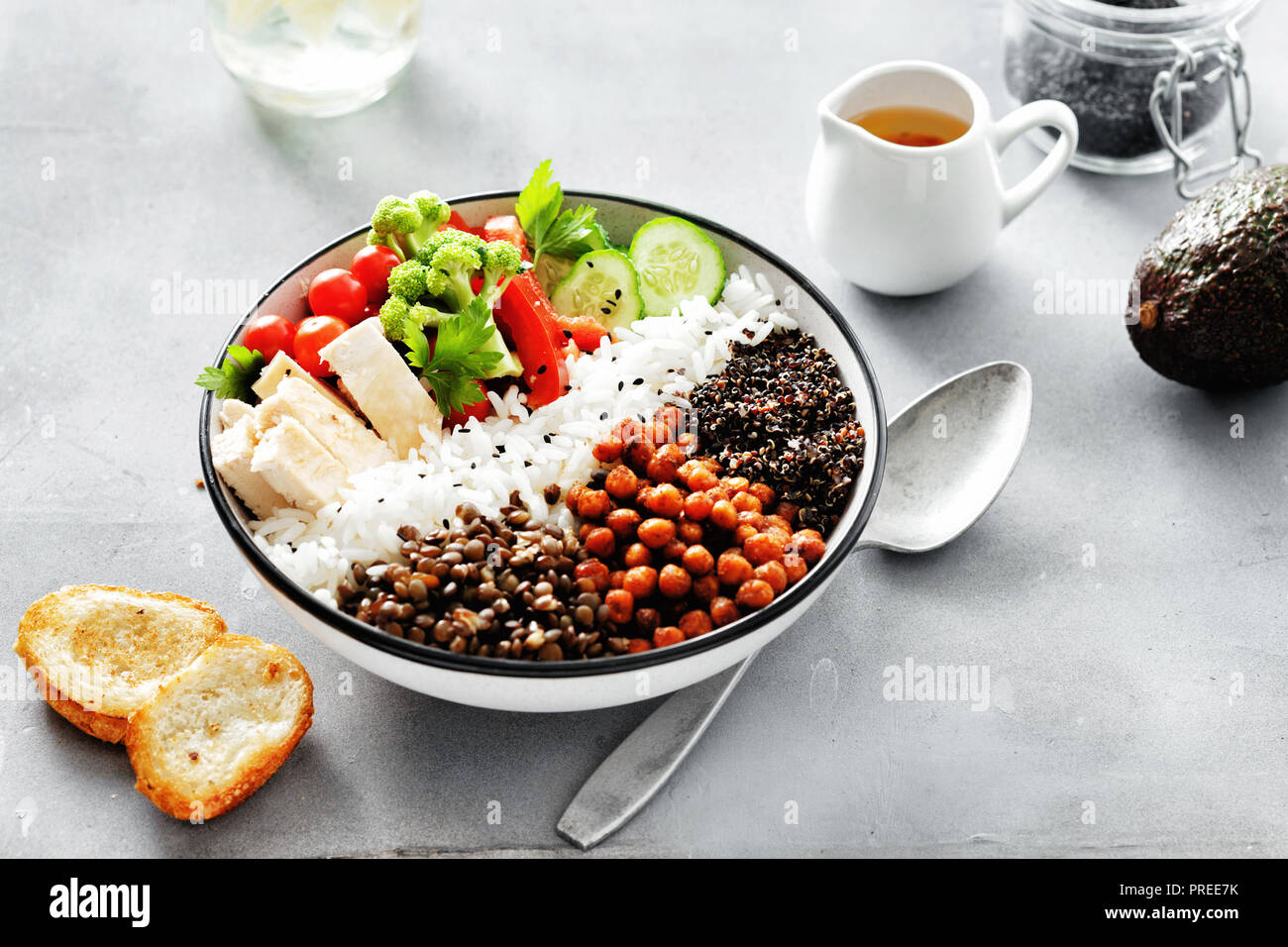 Buddha bowl. Clean and balanced healthy food concept. Rice, spicy chickpeas, black quinoa, vegetables and chicken fillet on gray concrete background t Stock Photo