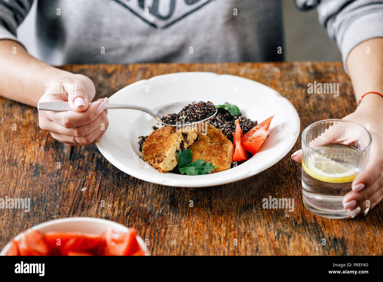 Woman is having lunch fried prunes oat cutlets with black quinoa Stock Photo