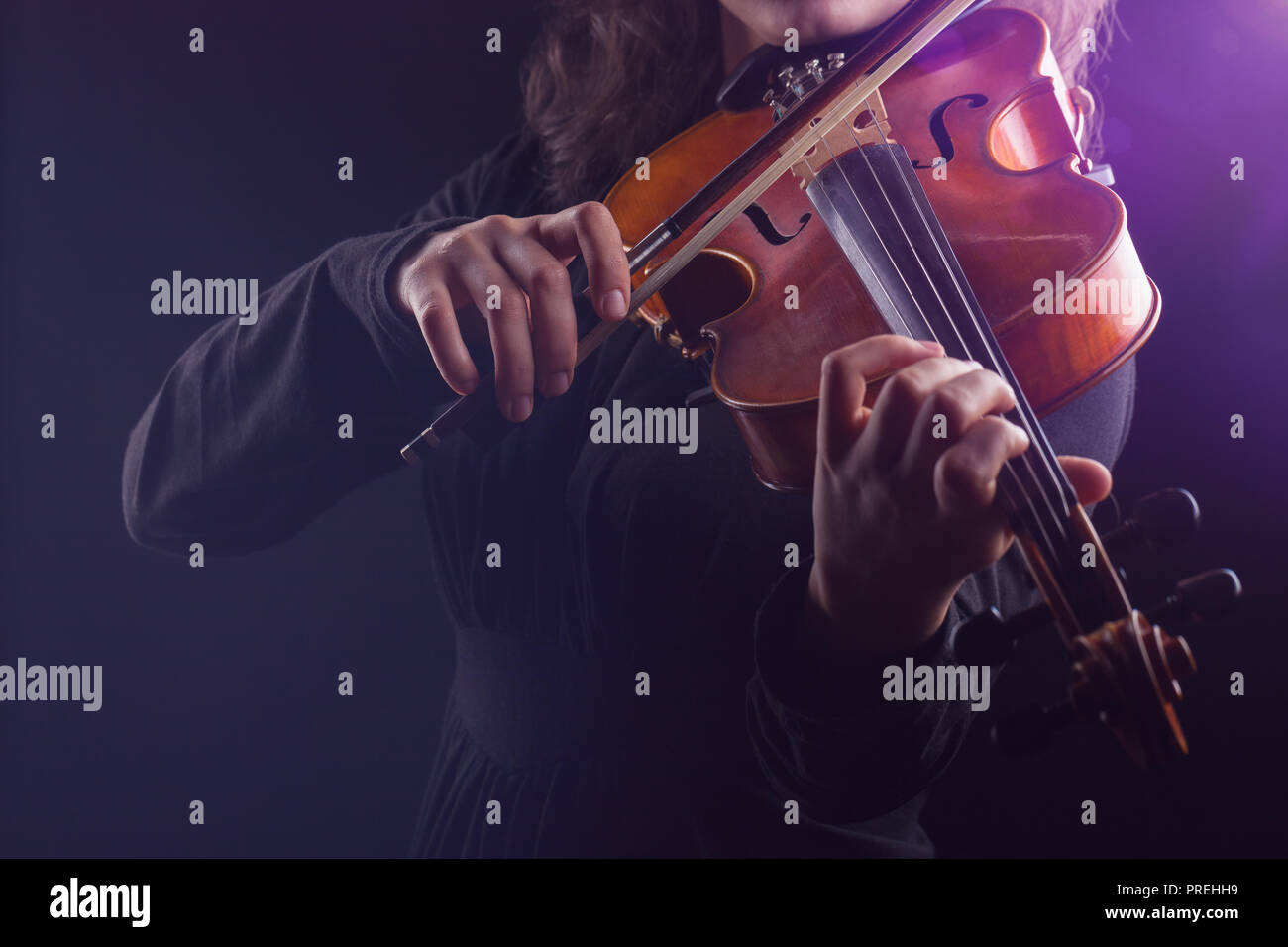 Young girl playing the violin on dark background Stock Photo