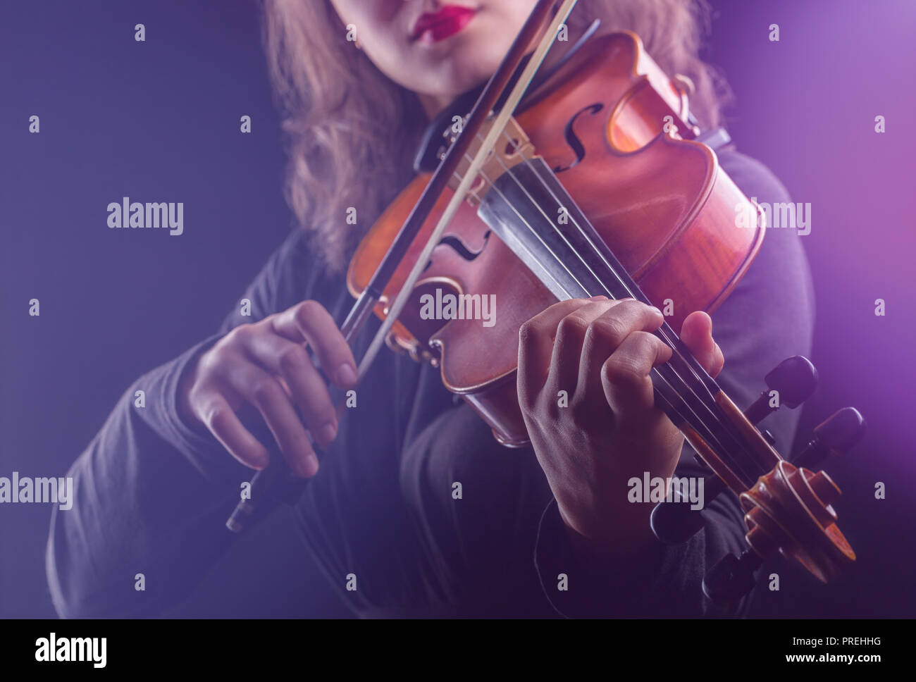 Close-up of a woman playing the violin on dark background Stock Photo