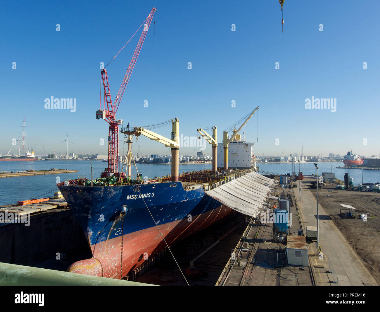 Cargo ship in dry dock for maintenance in the port of Antwerp, Belgium with more of the port visible Stock Photo