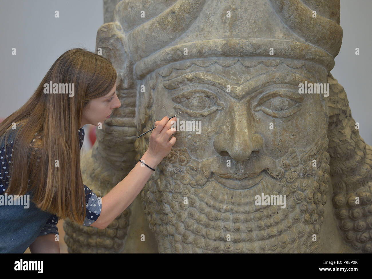British Museum stone conservator Kasia Weglowska, prepares a head of an Assyrian winged bull, from the palace of Ashurbanipal's father, Esarhaddon, at Nimrud 670BC. The head weighing 1.8 tonnes is part of the final installations for the I Am Ashurbanipal: king of the world, king of Assyria, exhibition at the British Museum, London, which opens on 8 November 2018. Stock Photo