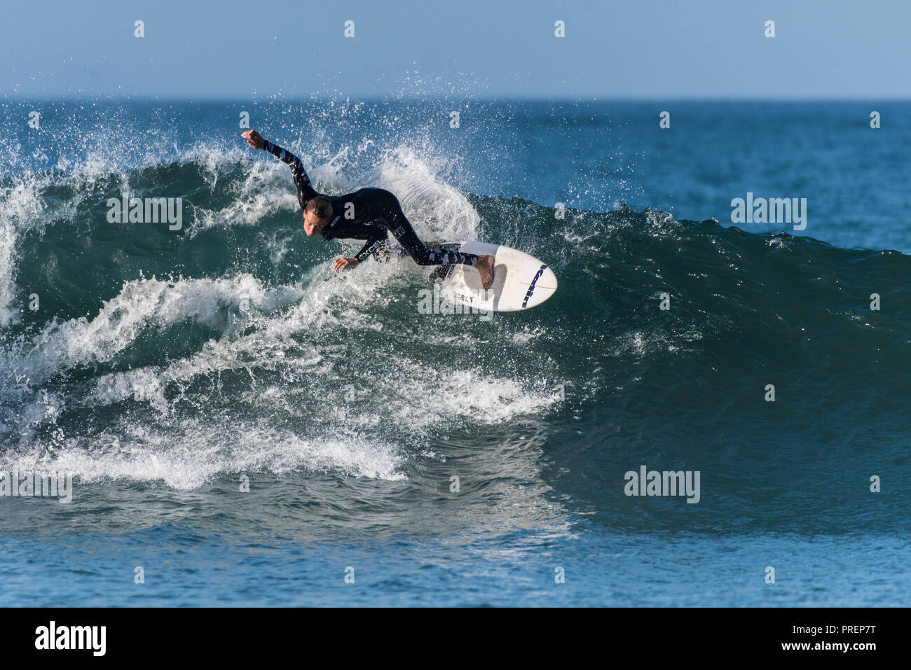 Surfer in black wetsuit ftakes a big and sweeping turn at Surfer's Knoll, Ventura, California on October 1, 2018. Stock Photo