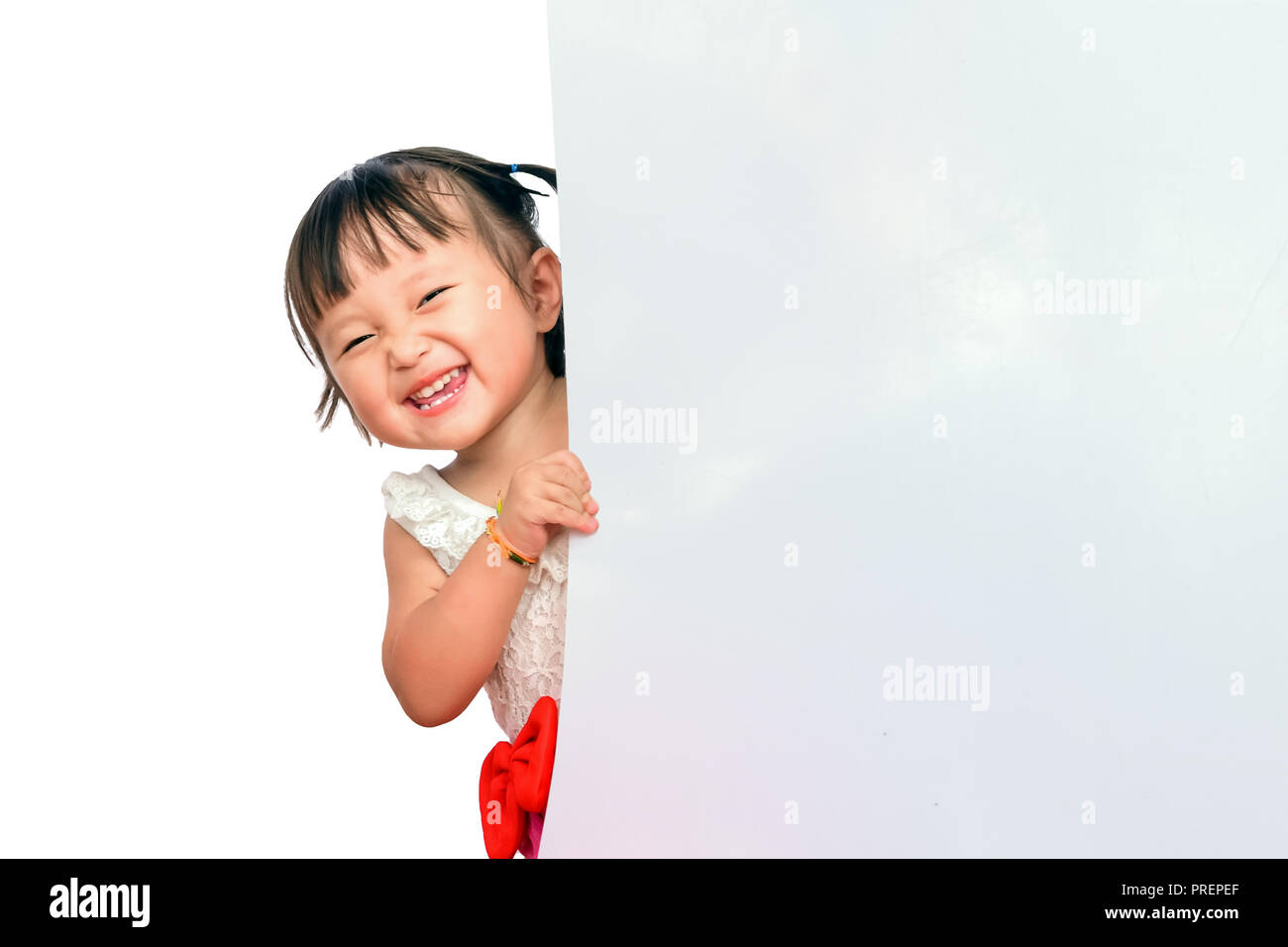 Happy Little asian children smile peeking out behind board. Space for copy composition for , website, magazine or graphic for commercial campaign design Stock Photo