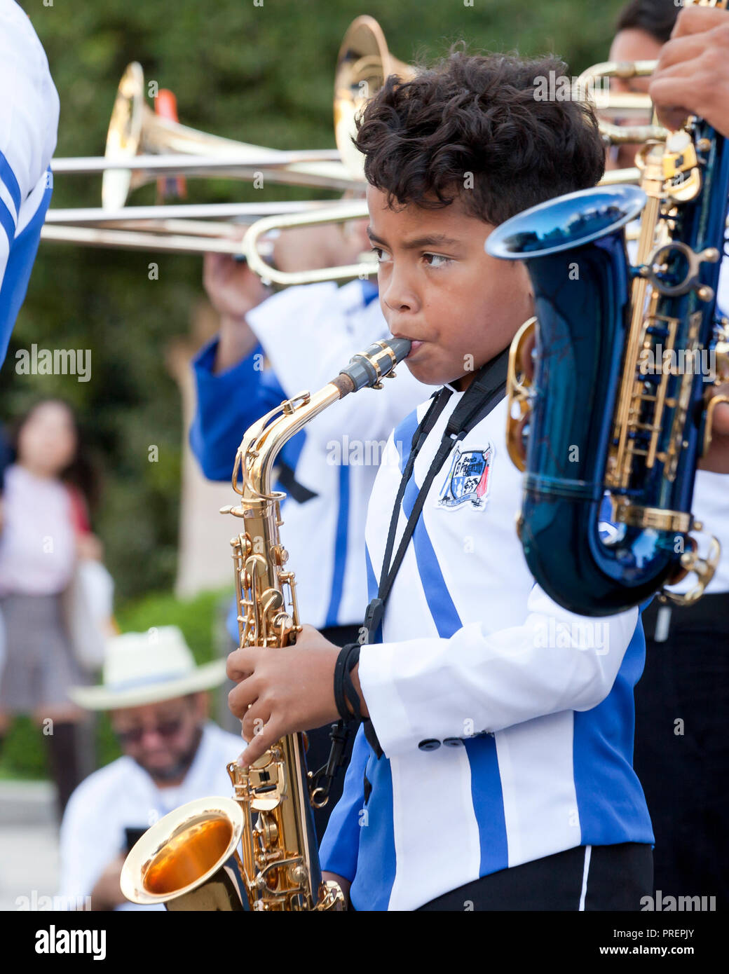 Preteen Hispanic boy playing saxophone in a marching band (sax player) - USA Stock Photo