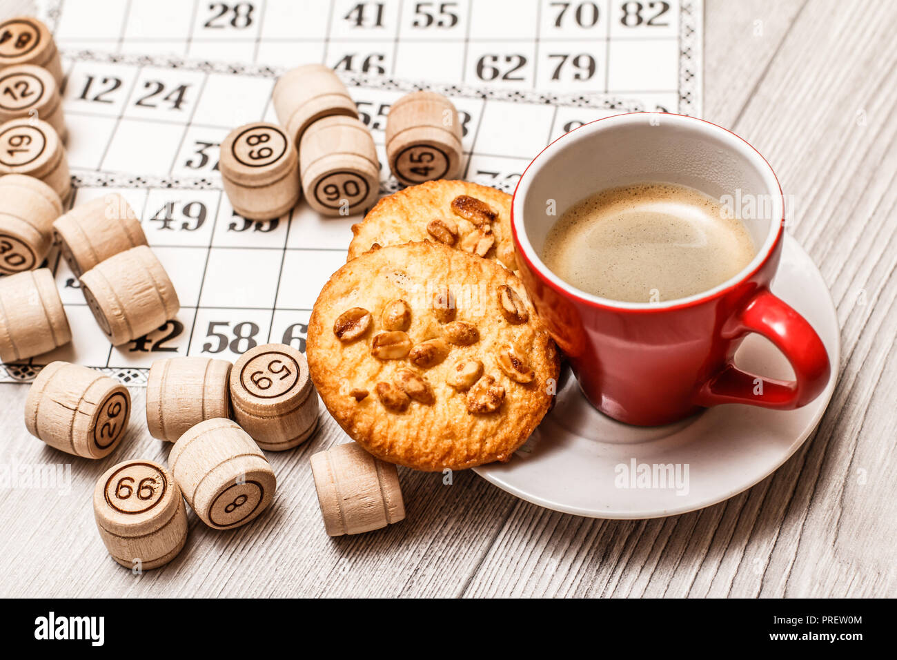 Board game lotto on white desk. Wooden lotto barrels and game cards for a game in lotto with cup of coffee and cookies on plate Stock Photo