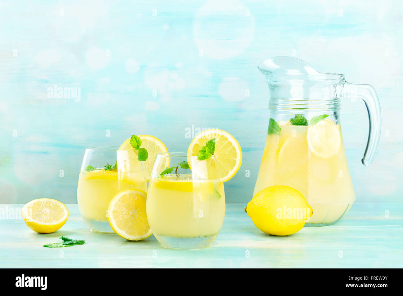 https://c8.alamy.com/comp/PREW9Y/a-side-view-of-homemade-lemonade-in-glasses-and-a-pitcher-with-fresh-lemons-and-mint-on-a-teal-background-with-copy-space-PREW9Y.jpg