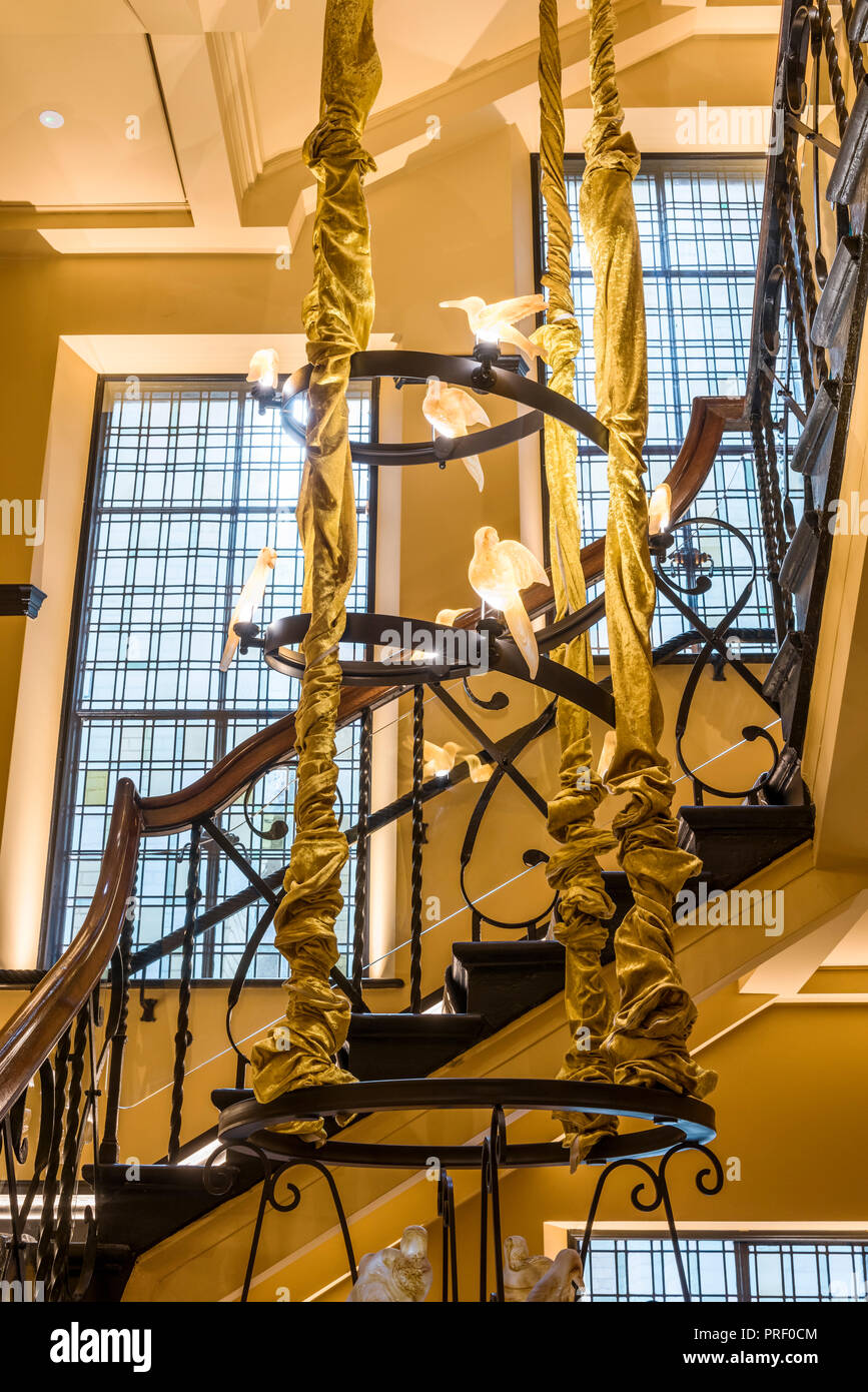 Original staircase running seven stories of building, with amber glass birds Stock Photo