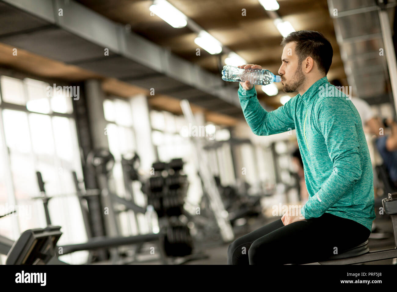Sportsman drinking water from bottle in the gym and resting Stock Photo ...