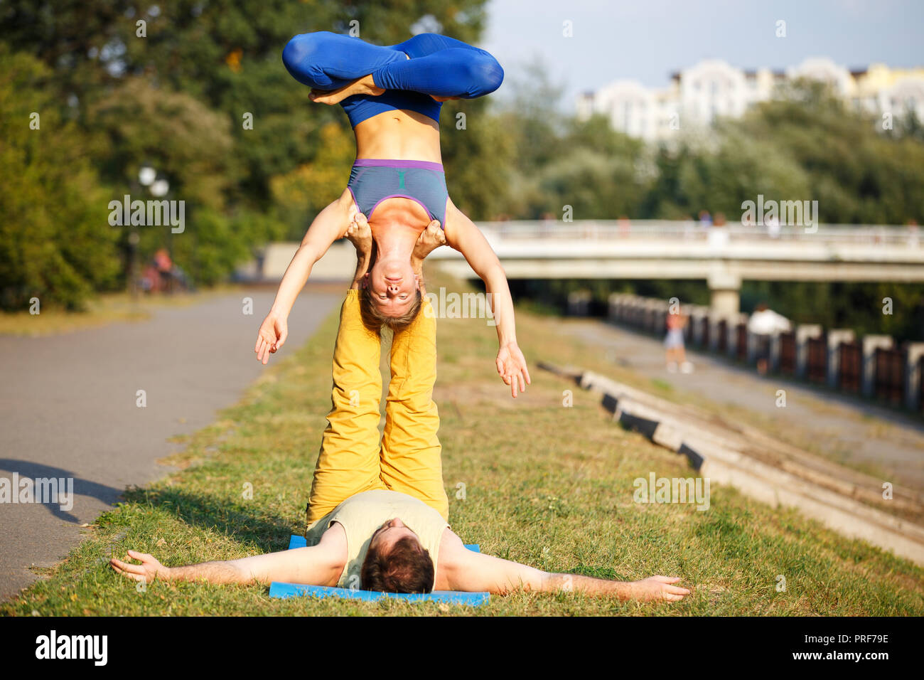 Couple of young man and woman practicing acro yoga in city park Stock Photo