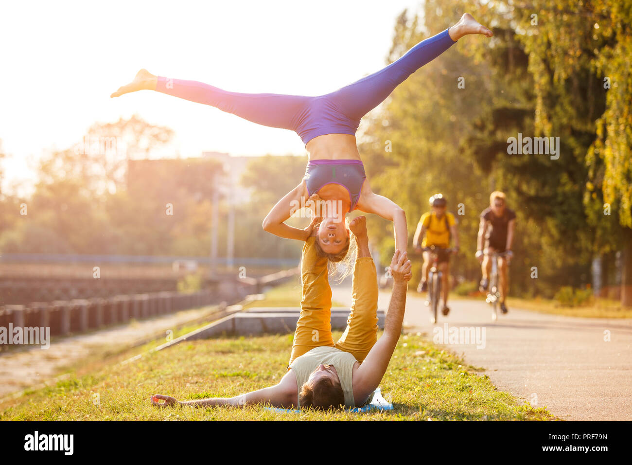 Couple of young man and woman practicing acro yoga in city park Stock Photo