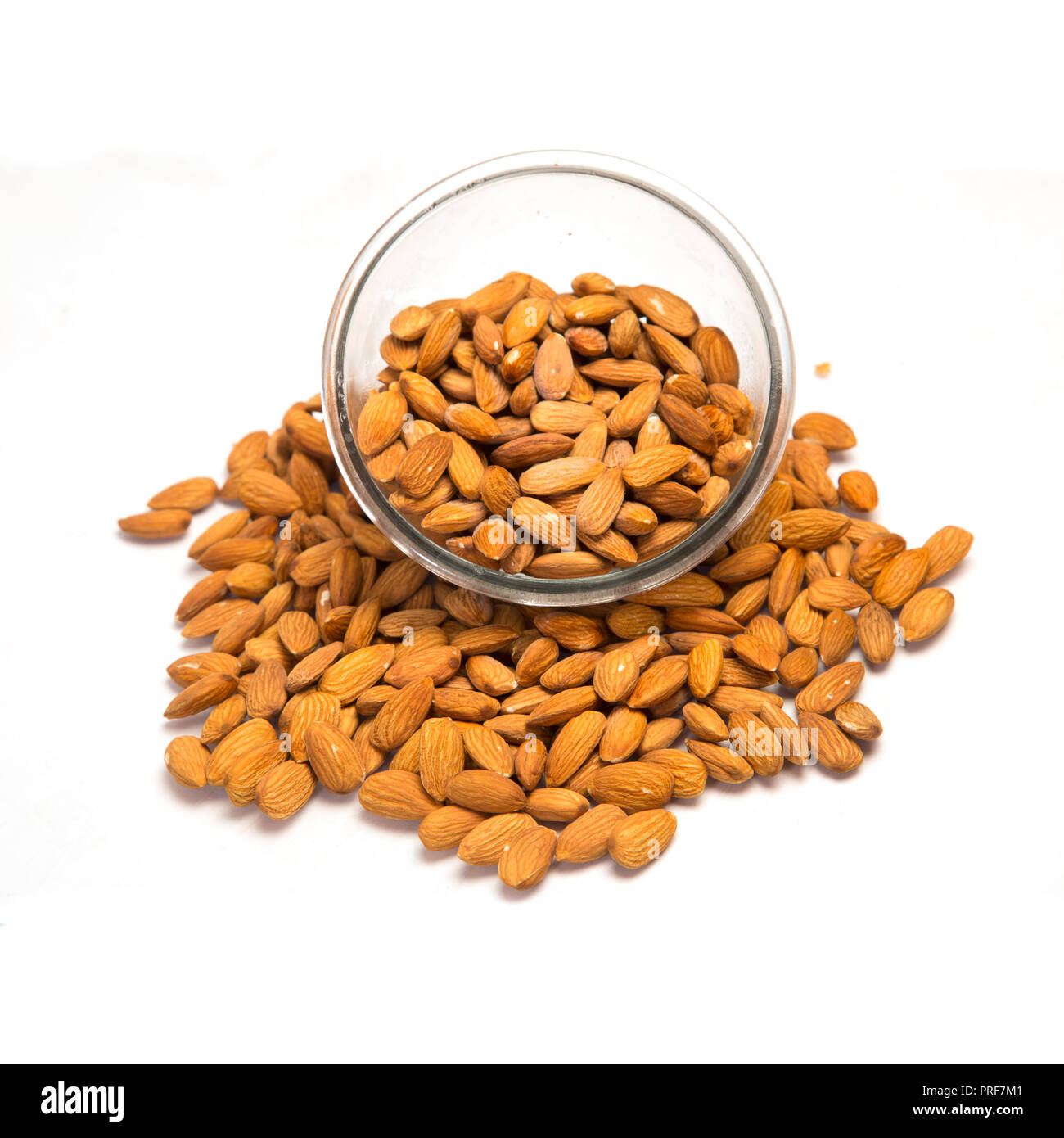 Almond heap, almond in transparent bowl isolated on white background
