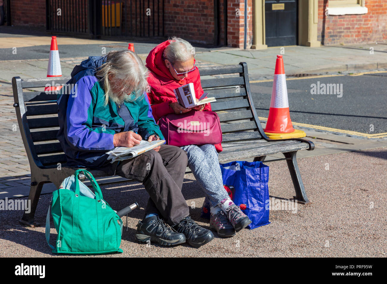 An elderly couple sit on a bench in the morning sun in Castle ...