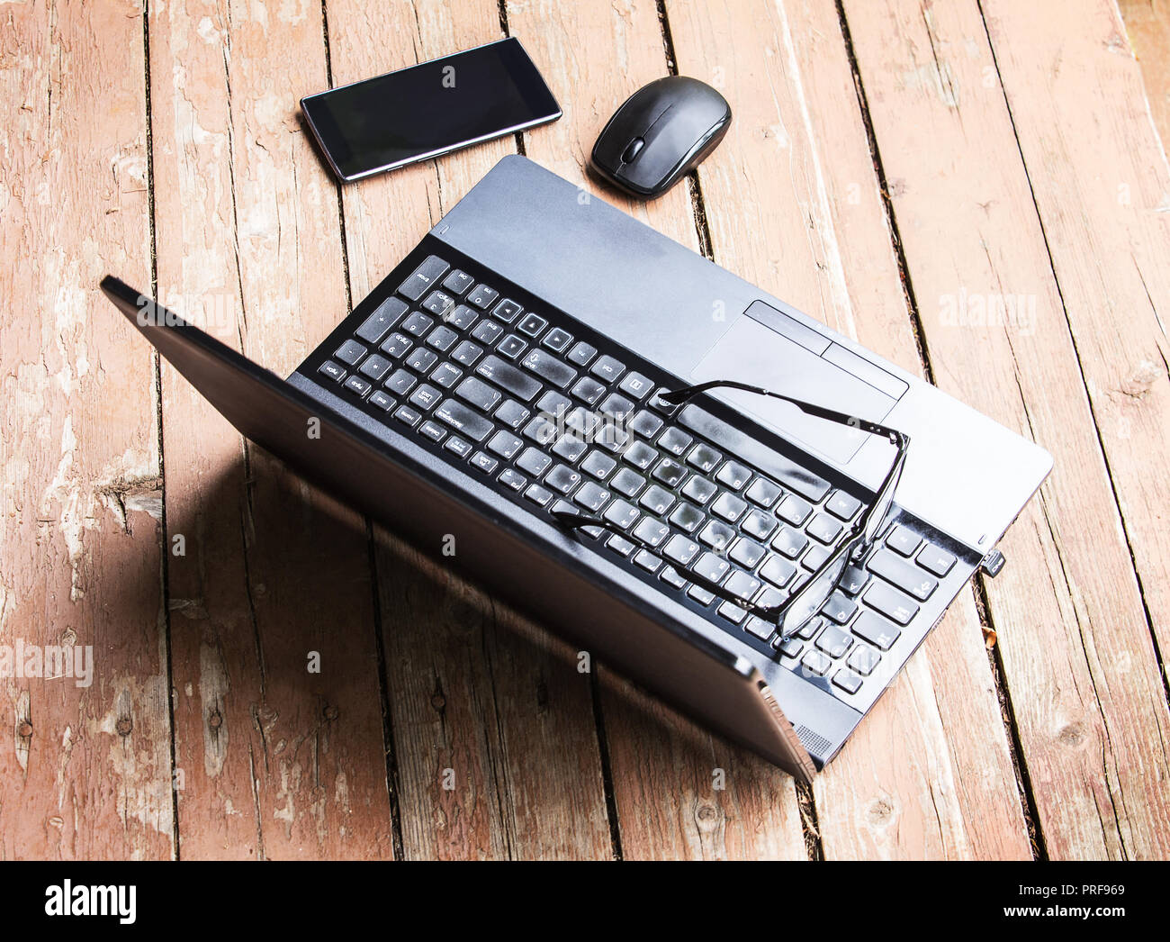 Laptop smartphone glasses computer mouse on an old wooden table Stock Photo