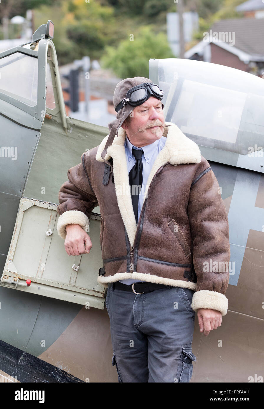 Re-enactor posing against a Spitfire replica and wearing 1940’s style pilots outfit at Welshpool 1940s Weekend Stock Photo