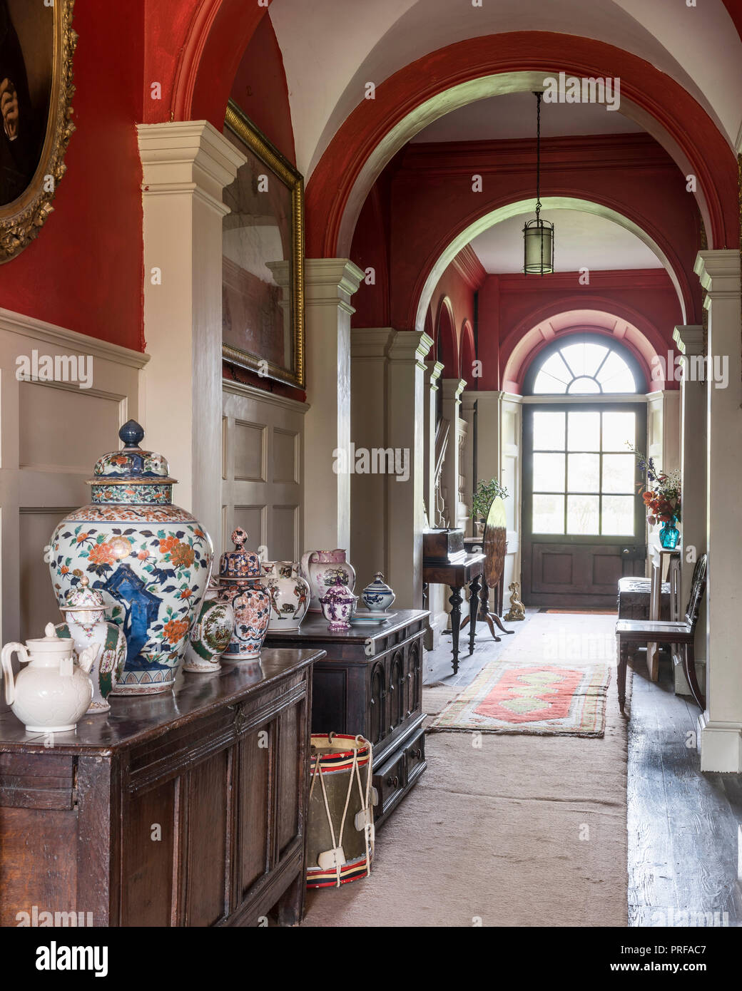 Red arched Georgian corridor lined with oriental porcelain and decorative ceramics Stock Photo