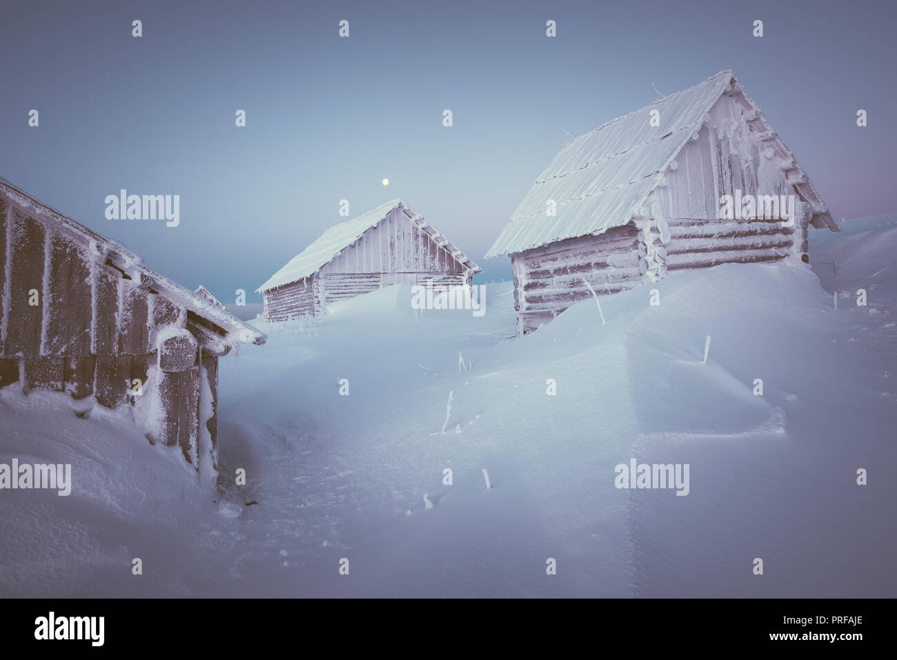 Old wooden house in a mountain village. Morning twilight. Winter ...