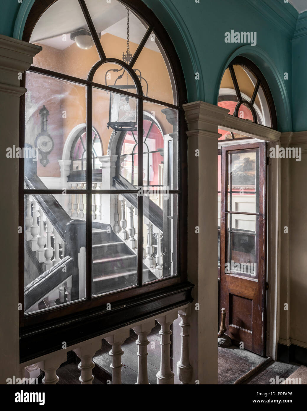 View through wooden door and windowframe to staircase with lantern Stock Photo