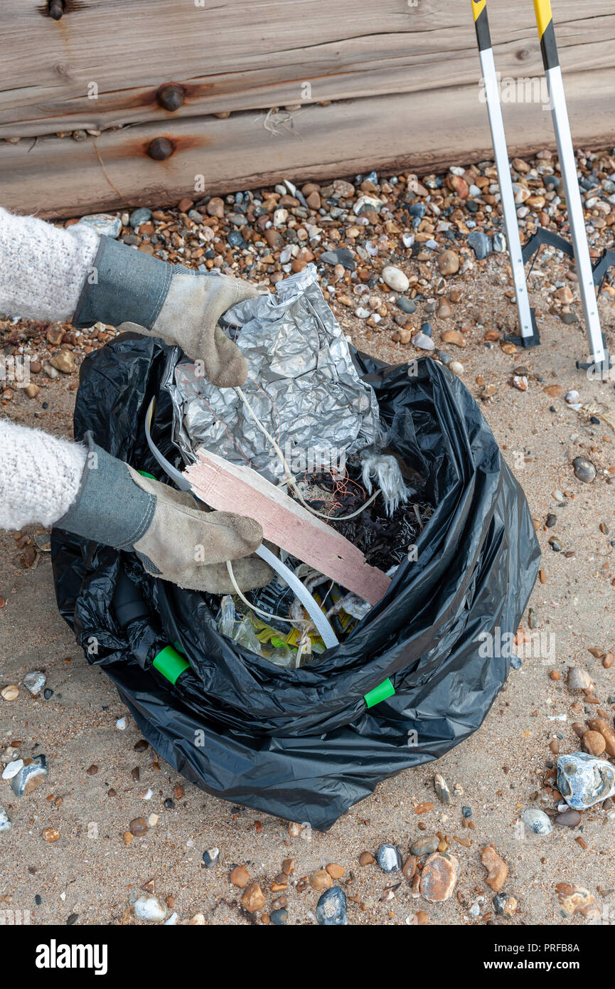 A woman wearing gloves puts plastic waste and rubbish collected from