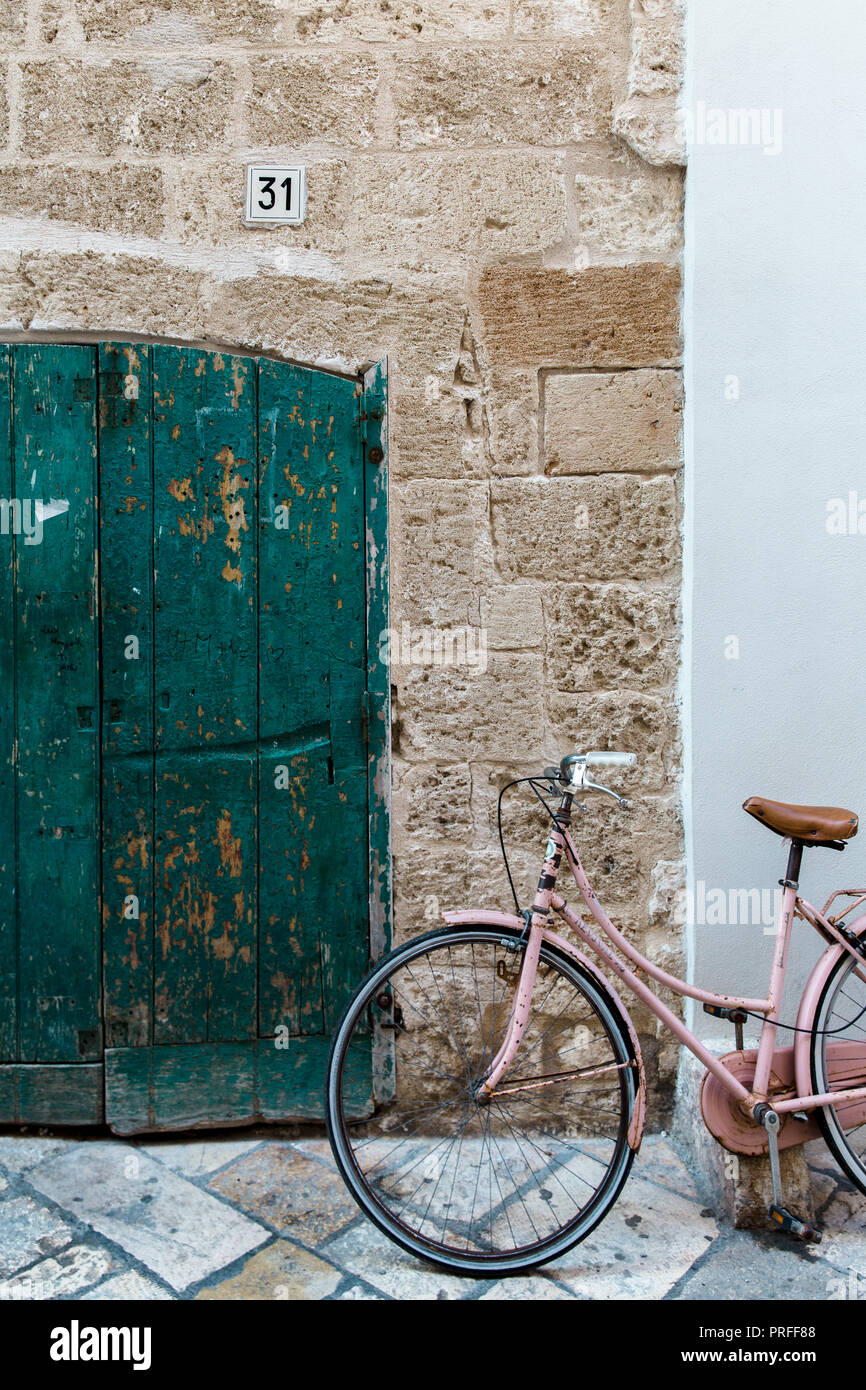 A bike in front of a traditional door in the old city of Polignano a Mare, Puglia, Italy Stock Photo