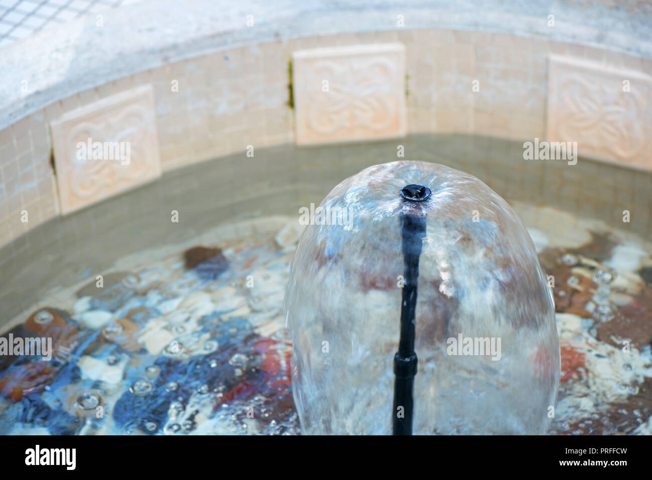 Small indoor fountain in a pool with decorative stones, pebbles and