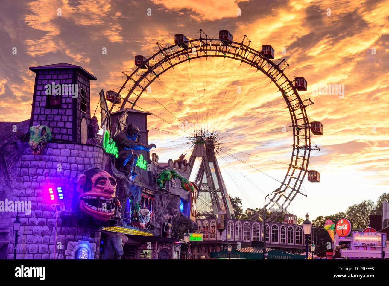 Wien, Vienna: Riesenrad (Ferris Wheel, giant wheel), creepy house 'Geisterschloss' in Prater Amusement park, fiery sunset, 02. Leopoldstadt, Wien, Aus Stock Photo