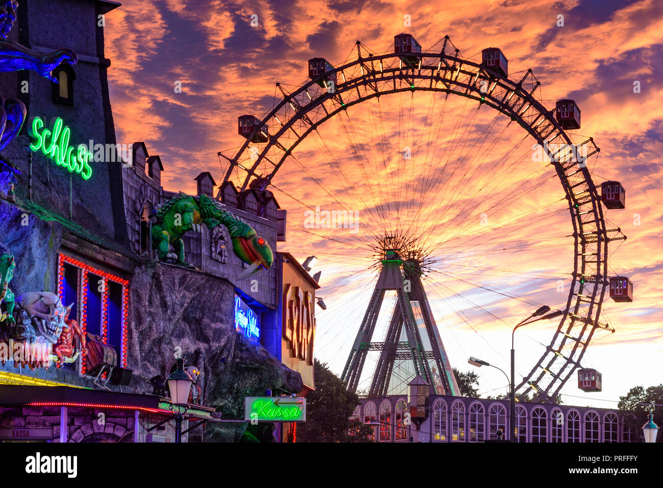 Wien, Vienna: Riesenrad (Ferris Wheel, giant wheel), creepy house 'Geisterschloss' in Prater Amusement park, fiery sunset, 02. Leopoldstadt, Wien, Aus Stock Photo