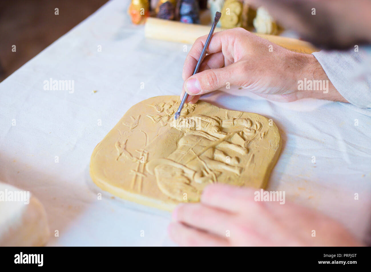 Professional male potter making clay stamp picture. Handwork, crafting