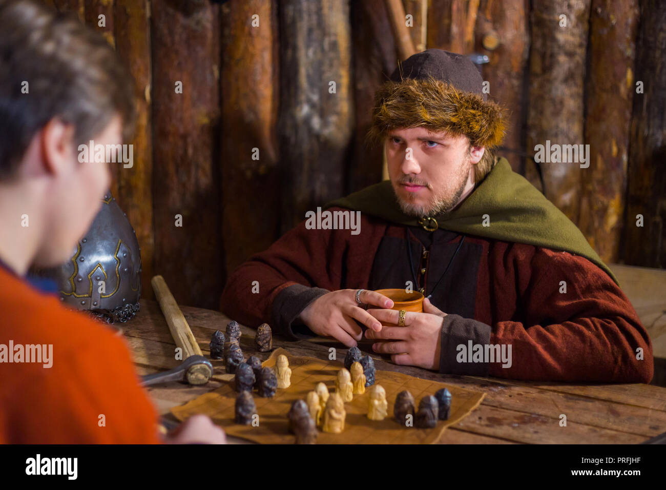 Two men in russian ethnic suit playing medieval popular strategy board game - tafl. Folk, competition and traditional concept Stock Photo