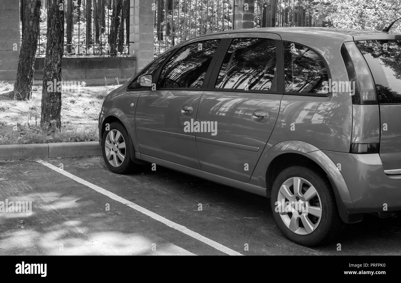 A fragment of a modern car in the Parking lot near the Park. Side view. Black-and-white image. Stock Photo