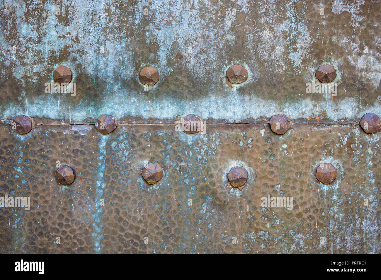 Texture of old weathered metal door with rivets. Vintage washed out rusty metal. Stock Photo