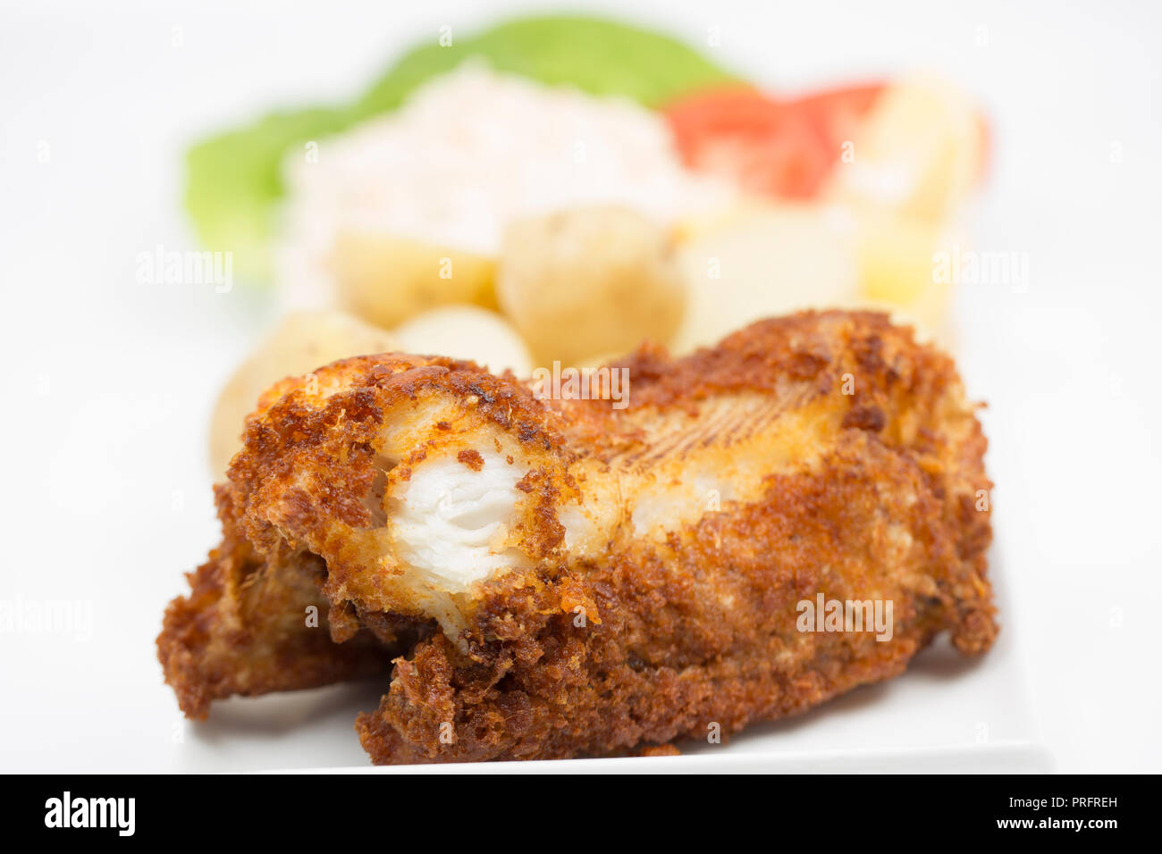 A deep fried section of a bull huss, served with boiled potatoes, salad and coleslaw, caught boat fishing on rod and line off the Dorset coast in the  Stock Photo