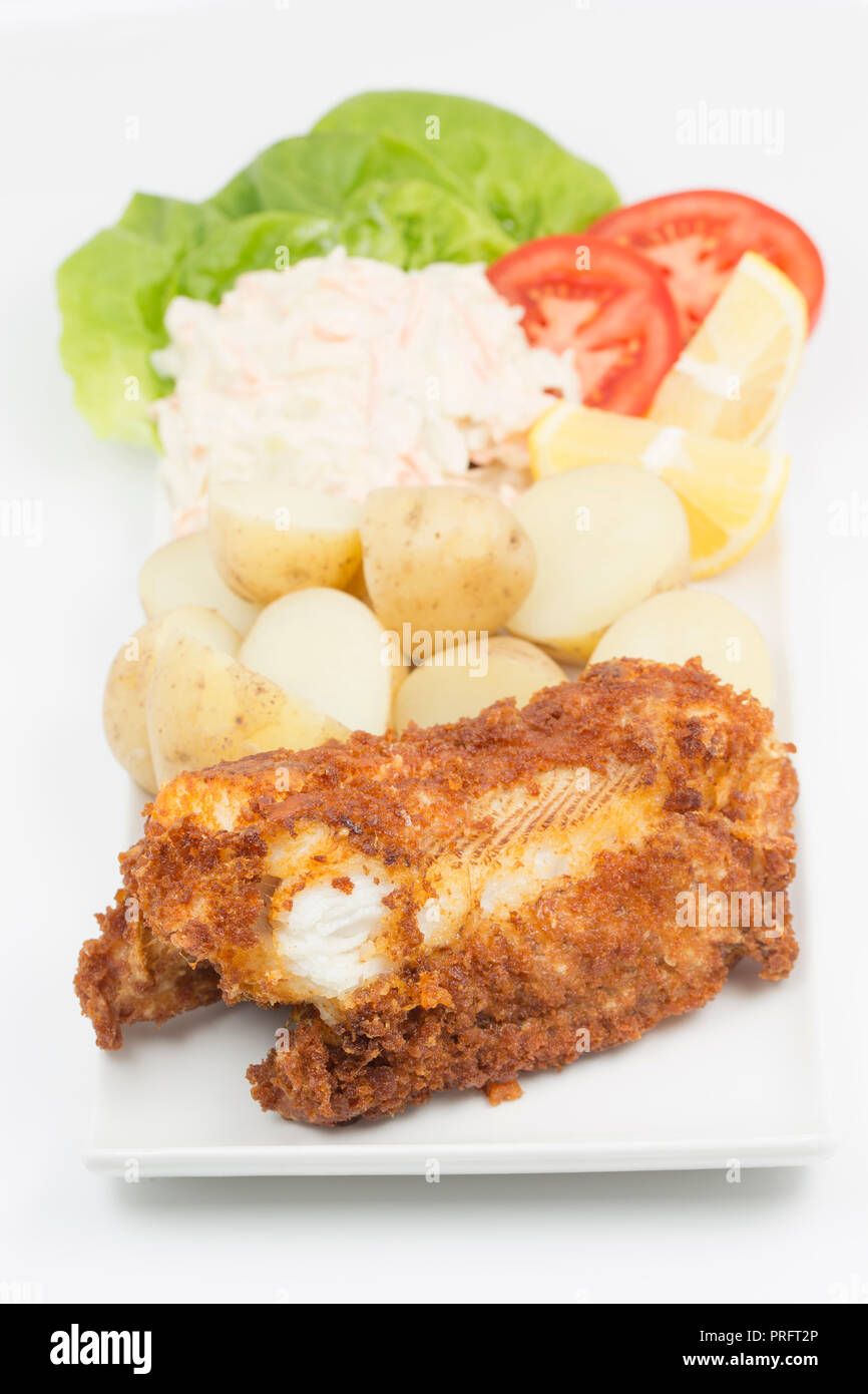 A deep fried section of a bull huss, served with boiled potatoes salad and coleslaw, caught boat fishing on rod and line off the Dorset coast in the E Stock Photo