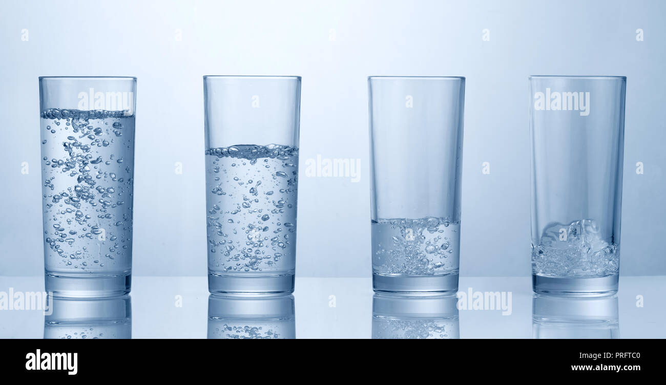 four glasses of vater with various amount of water inside Stock Photo