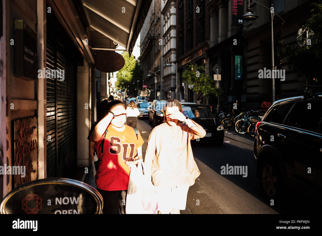 Two People on a street in Melbourne, Australia, shielding their eyes from the sun Stock Photo
