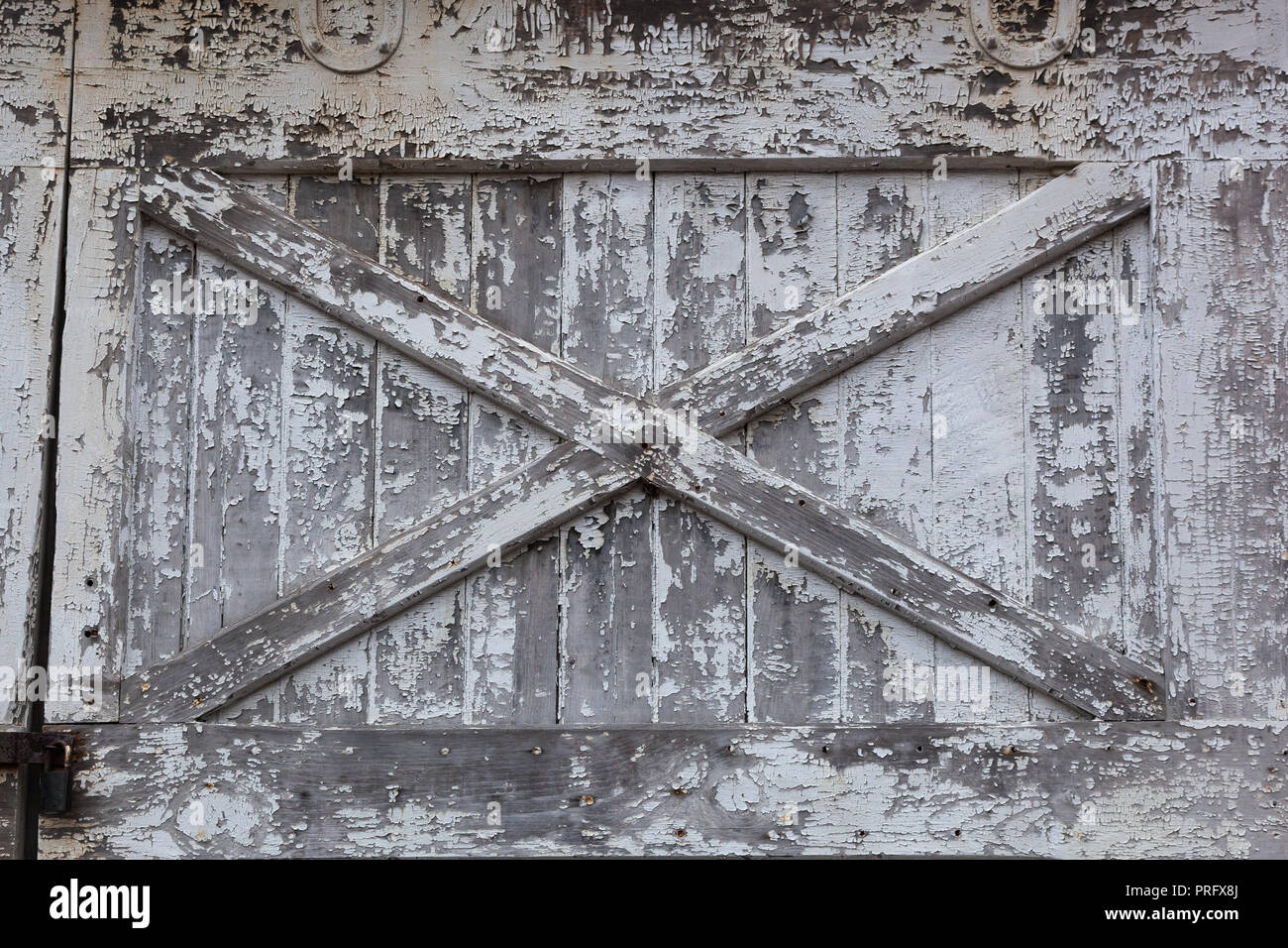 An Old White Barn Door Has Peeling Paint And Is In Need Of Repair
