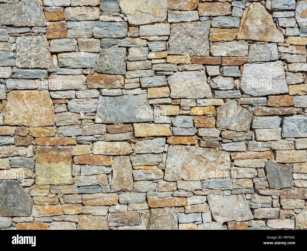 Stone granite wall made of stacked pieces stones. Full frame image as background. Stock Photo