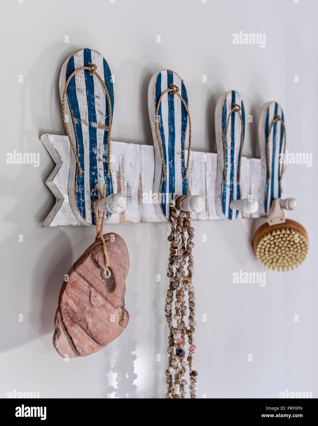 Seashell necklace with backbrush and stone, hang from flip-flop peg board in Devon cottage Stock Photo
