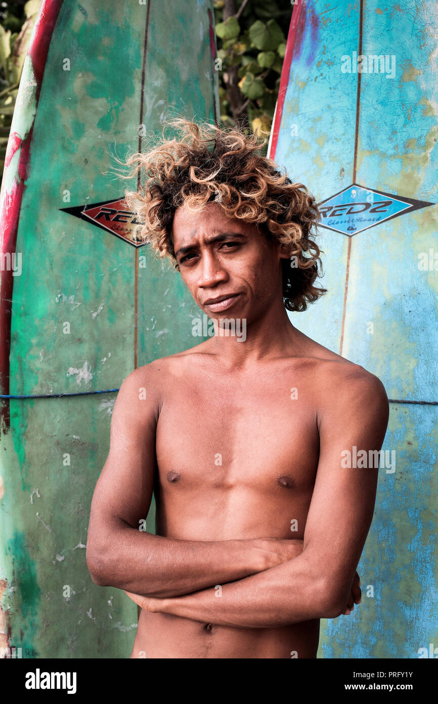 Portrait of young Balinese man hiring surfboards on Kuta beach, Bali