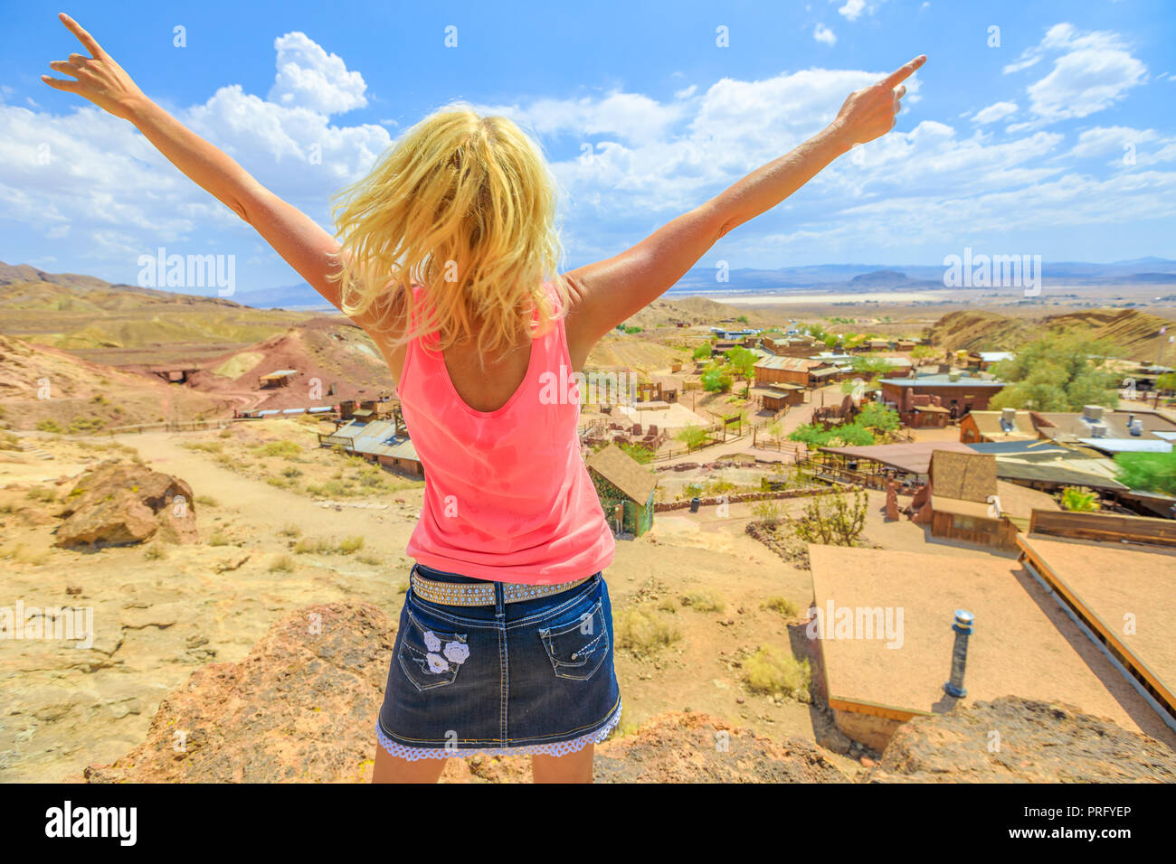 Woman with open arms enjoying at aerial view of Calico atop of overlook. Calico is a Ghost Town and former Mining town in Calico Mountains of Mojave Desert region of California, United States. Stock Photo
