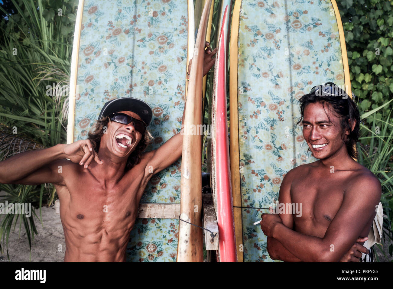 Happy Balinese men renting surfboards at Kuta Beach in Bali, Indonesia