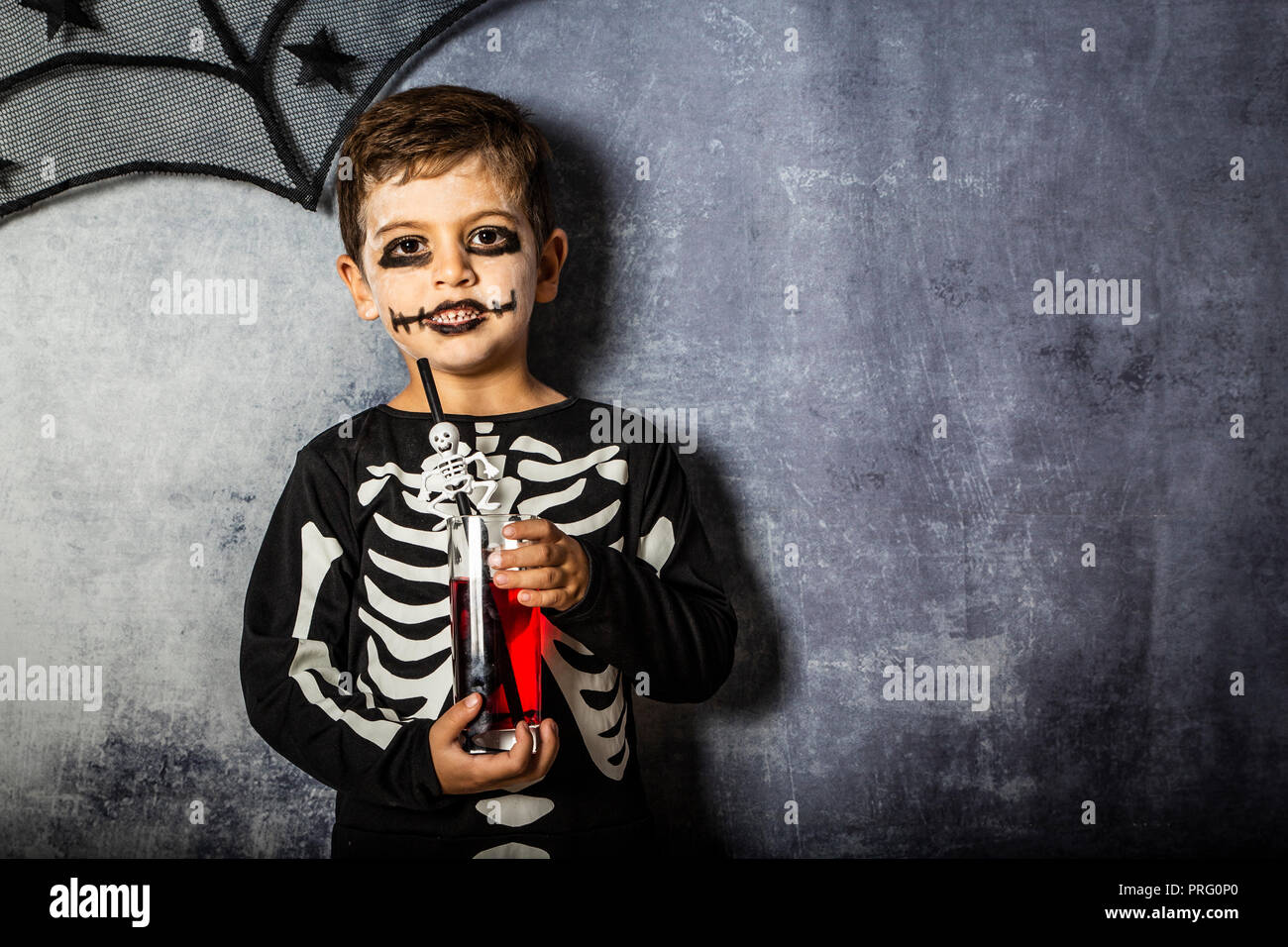 Little kid in a skeleton costume drinking fake blood on Halloween Stock