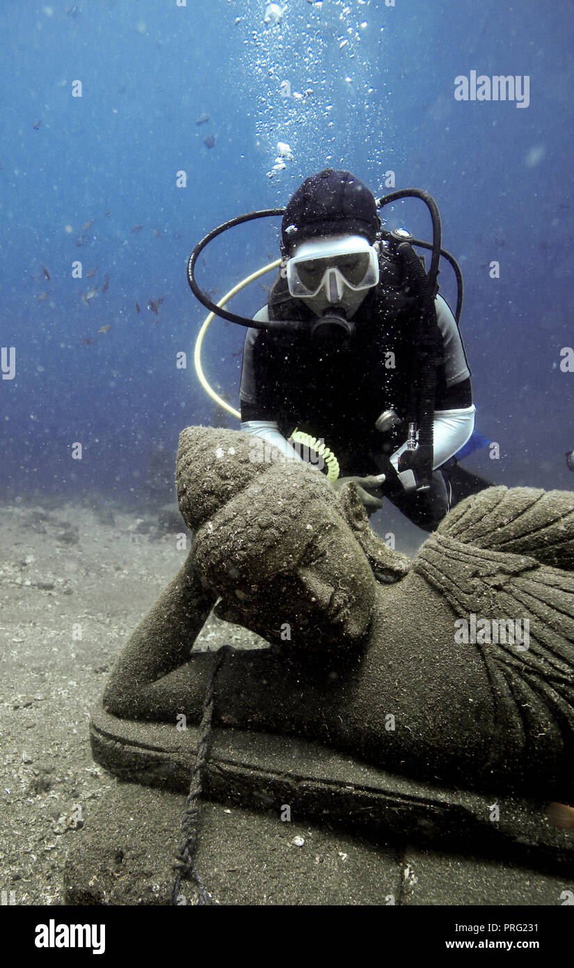 Scuba diver looking at Buddha statue in underwater sculpture garden in Tulmaben, Bali Stock Photo