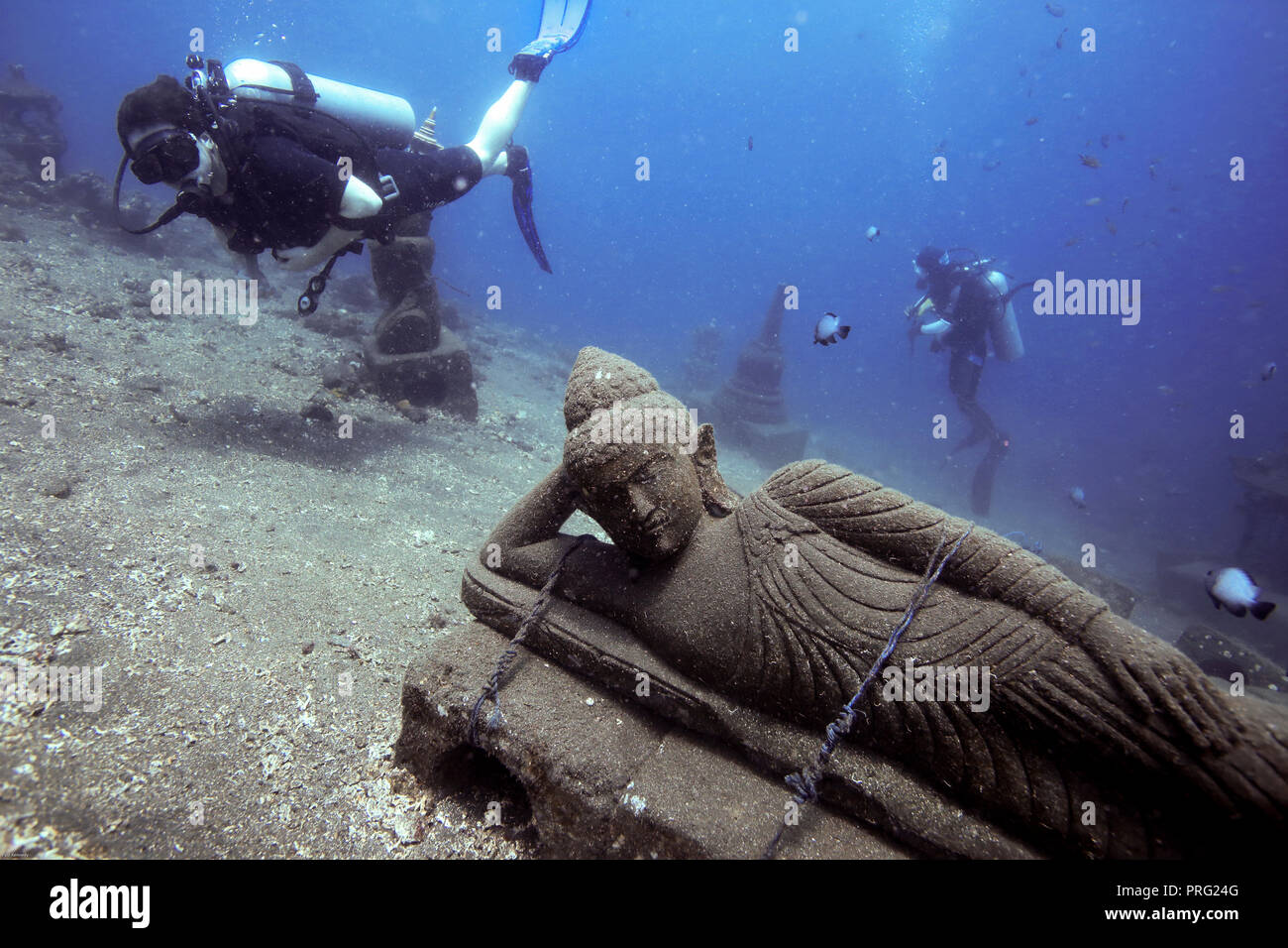 Scuba divers looking at Buddha statue in underwater sculpture garden in Tulmaben, Bali Stock Photo