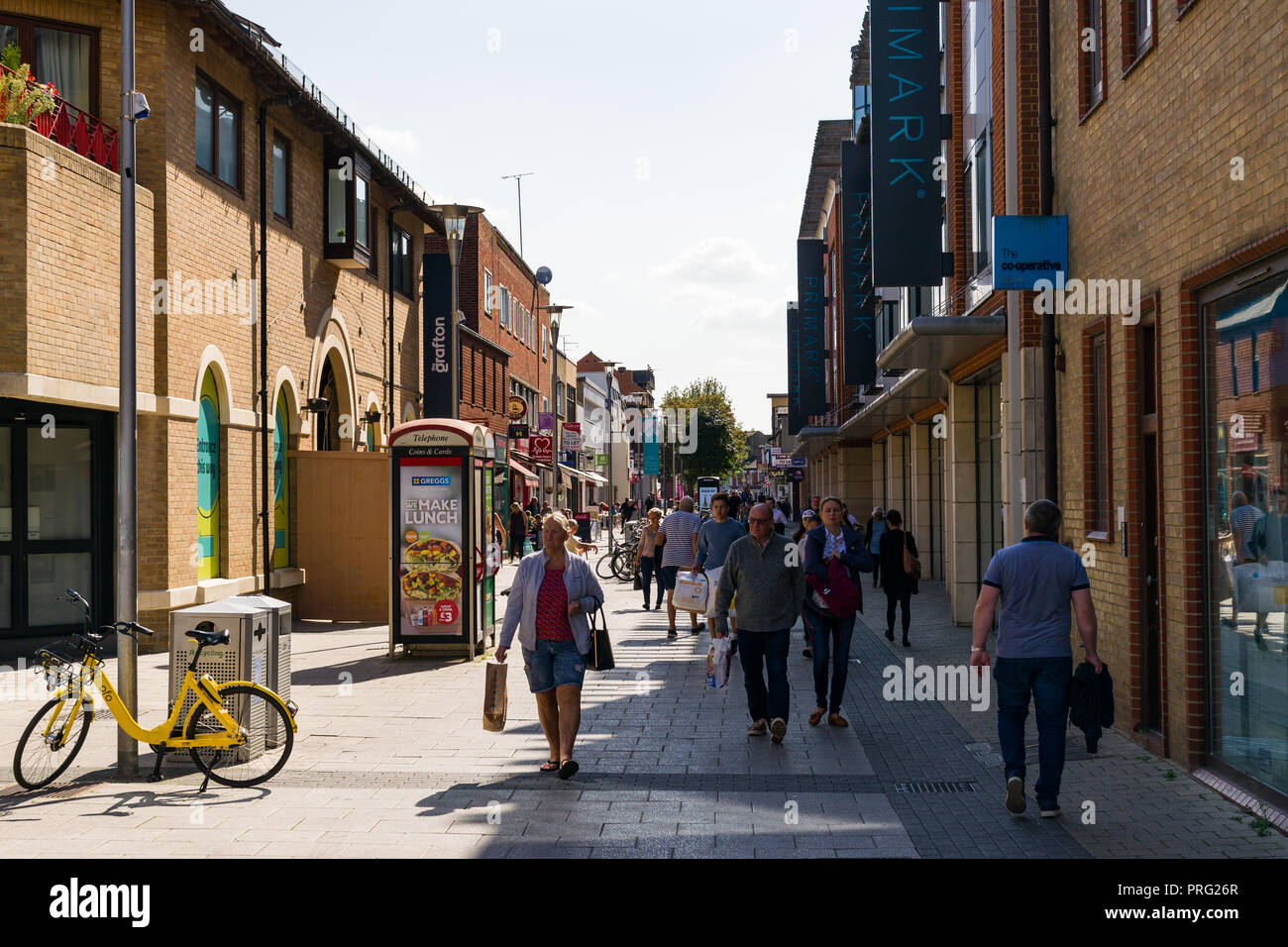 View along Burleigh Street with shoppers walking along the pavement, Primark and the Grafton Centre line the street, Cambridge, UK Stock Photo
