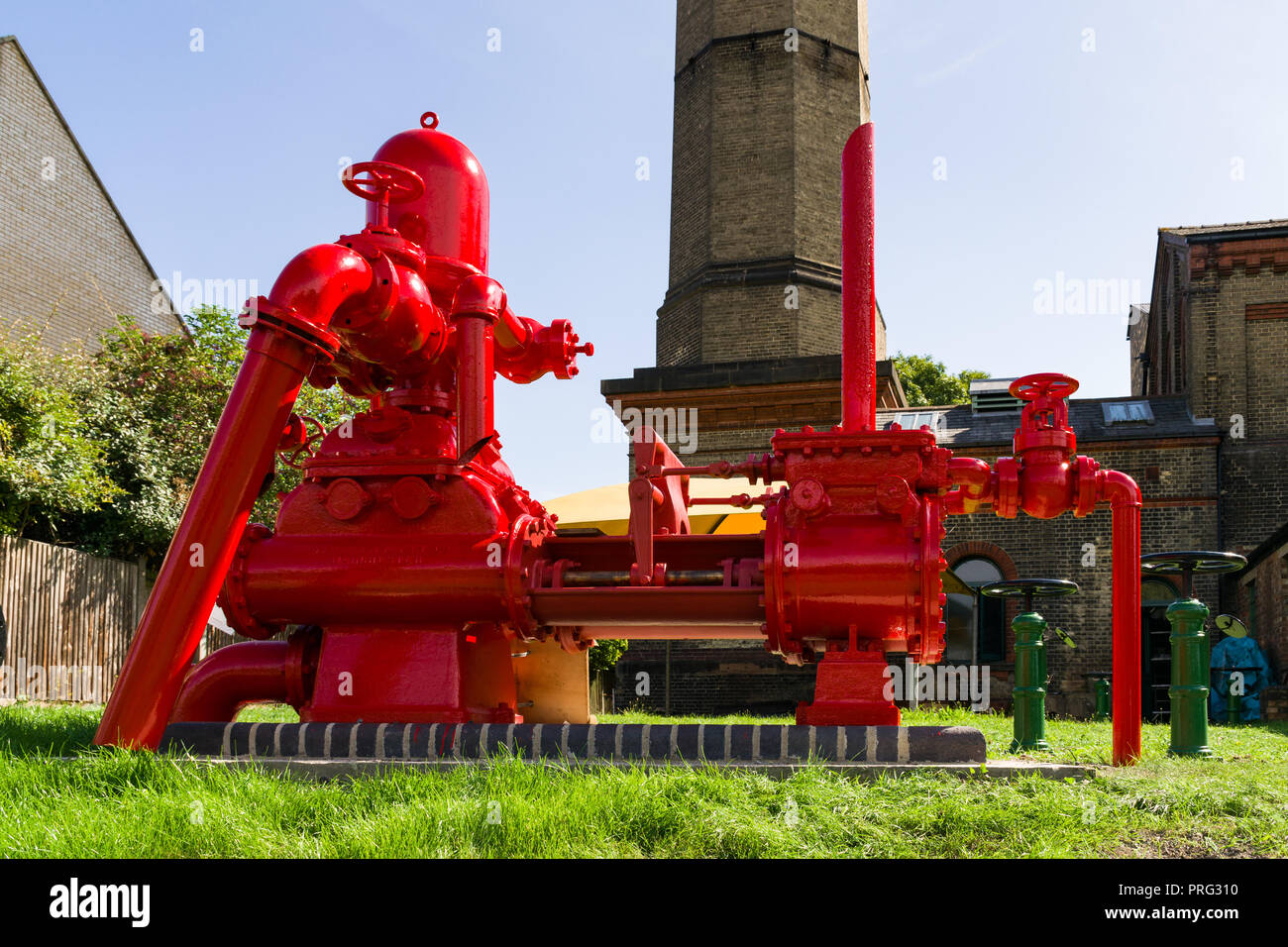 A large red water pump on display in the gardens of the Cambridge