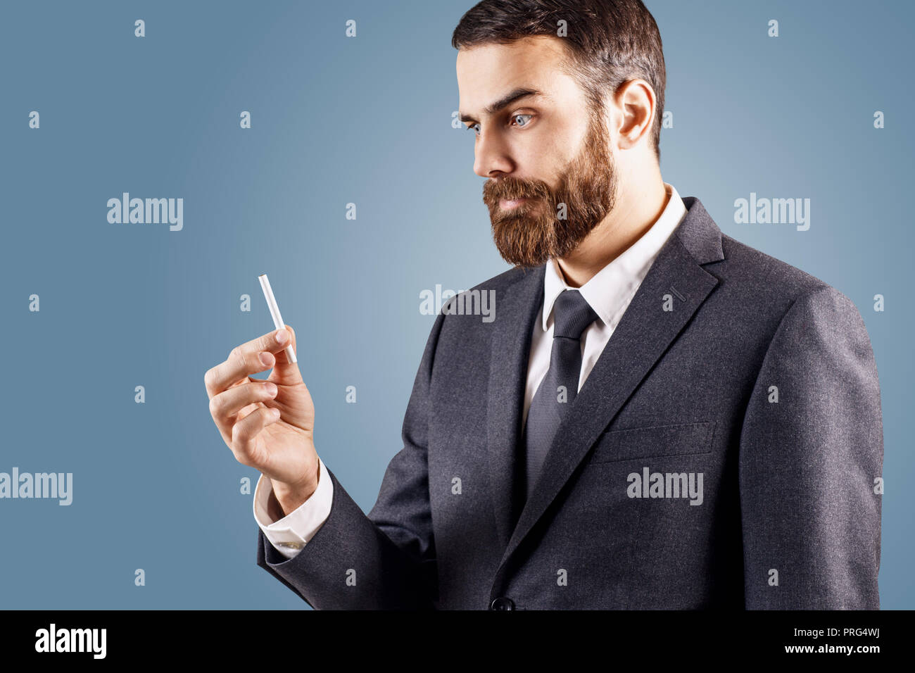 Bewildered businessman looking on cigarette in hand. Stock Photo